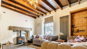 A cozy living room with a fireplace, wooden beams, and a large window. - 5 Bed in Richmond (oc-81457) (Gunnerside)