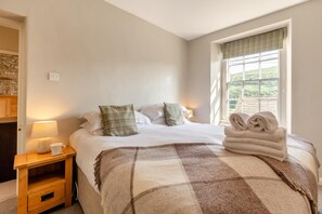 Ein Hotelzimmer mit Bett, Nachttisch mit Lampe, Fenster mit Blick und gestapelten Handtüchern.