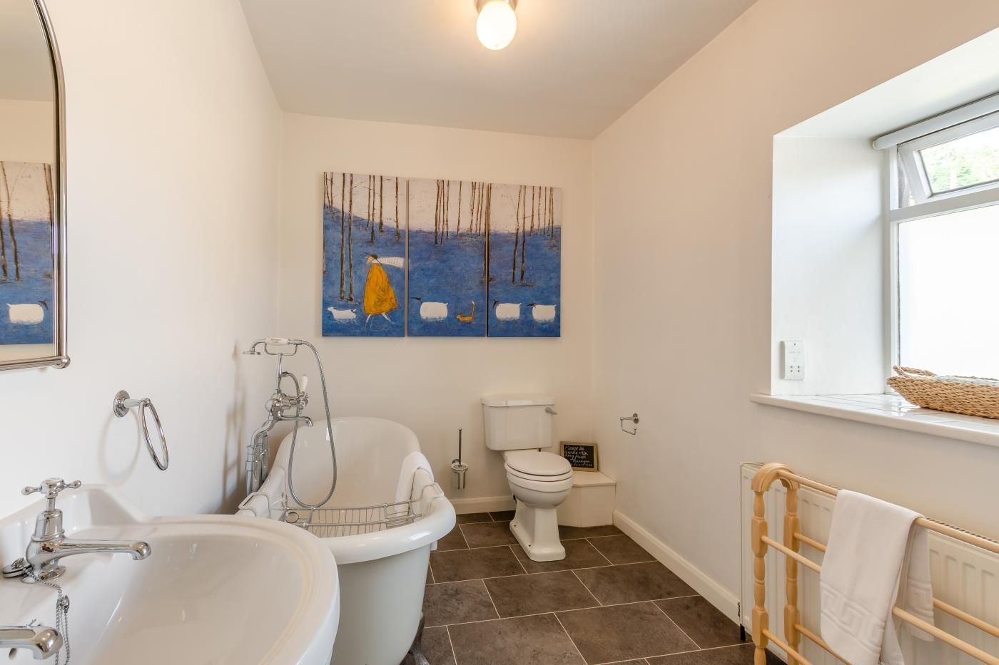 Une salle de bain avec une baignoire, un lavabo, des toilettes et une fenêtre donnant sur un beau paysage.