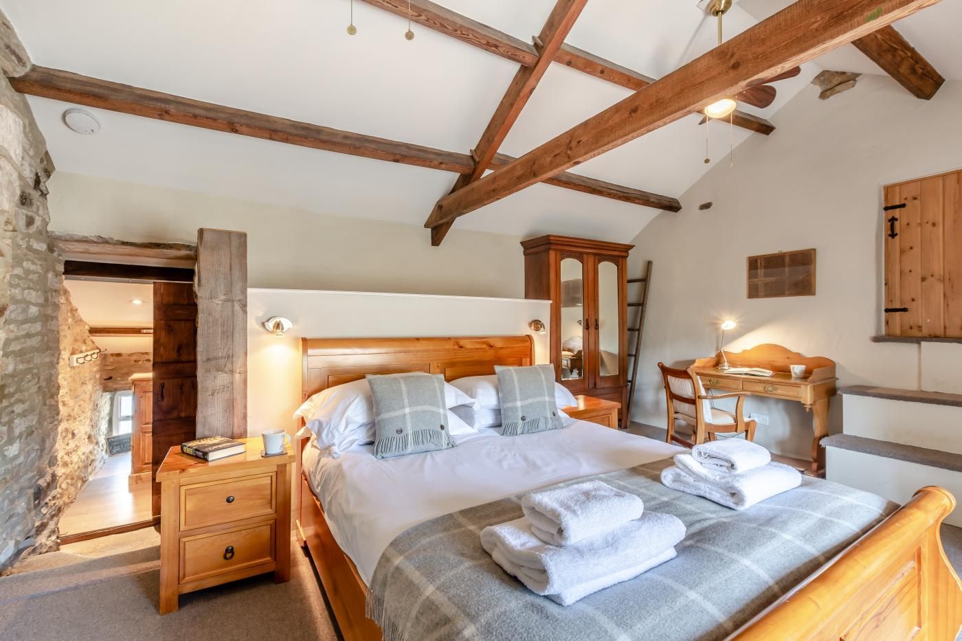 Une chambre à coucher avec un lit en bois, des tables de chevet, une armoire et un bureau avec une chaise.