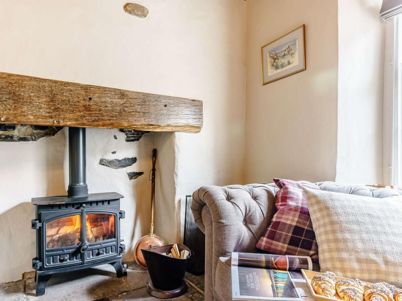 A cozy room with a wood-burning stove, a cushioned sofa, and a book.