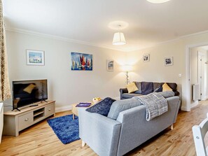 Ein Wohnzimmer mit Sofa, Fernseher und Kunstwerken an der Wand.