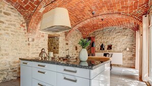 A kitchen with a large island, stone walls, and a brick ceiling. - Casa Carlin, Cascine Crema: large house that sleeps up to 11 people, with a 20x14 m pool (Piemonte)