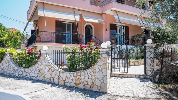 A two-story house with a stone wall and metal gate. - Stavros Two-Bedroom House by Konnect (Corfu)