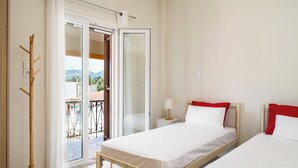 A hotel room with a bed, a bedside table, a lamp, and a view of the outdoors. - Stavros Two-Bedroom House by Konnect (Corfu)