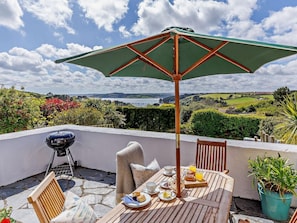 Eine Terrasse mit Tisch, Stühlen, einem Grill und Blick auf die Landschaft.