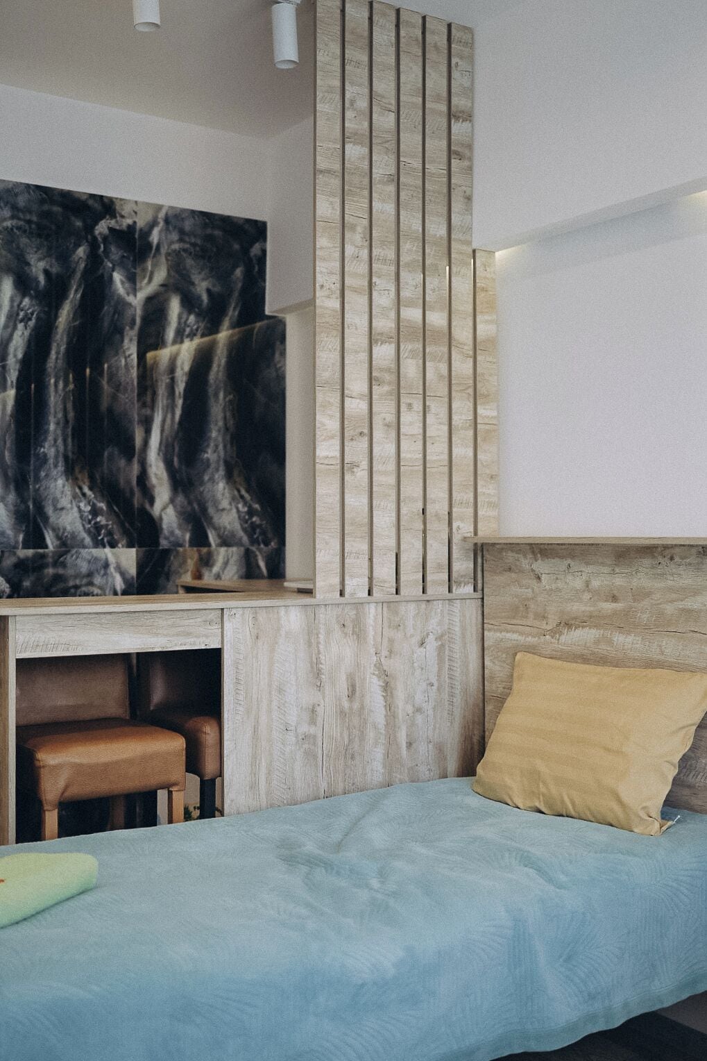 A bedroom with a bed, a desk, and a wall-mounted TV.