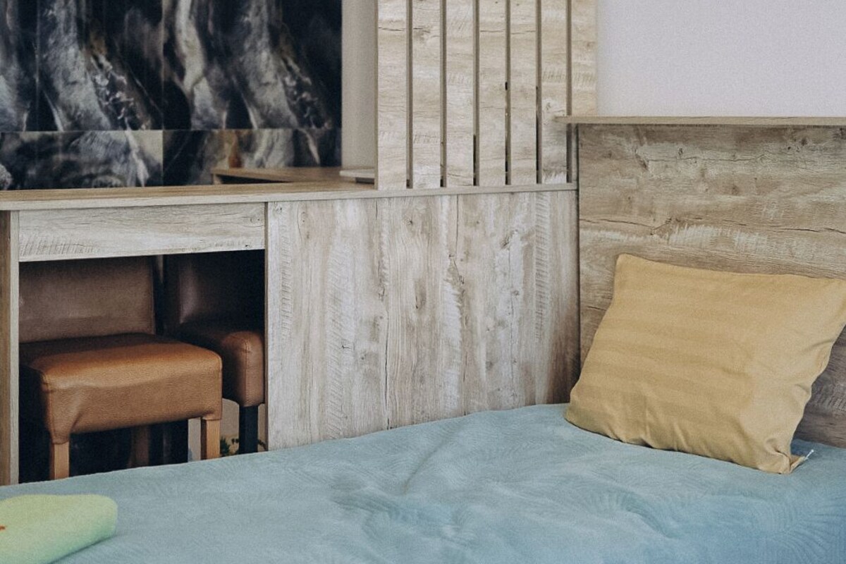 A bedroom with a bed, a desk, and a wall-mounted TV.