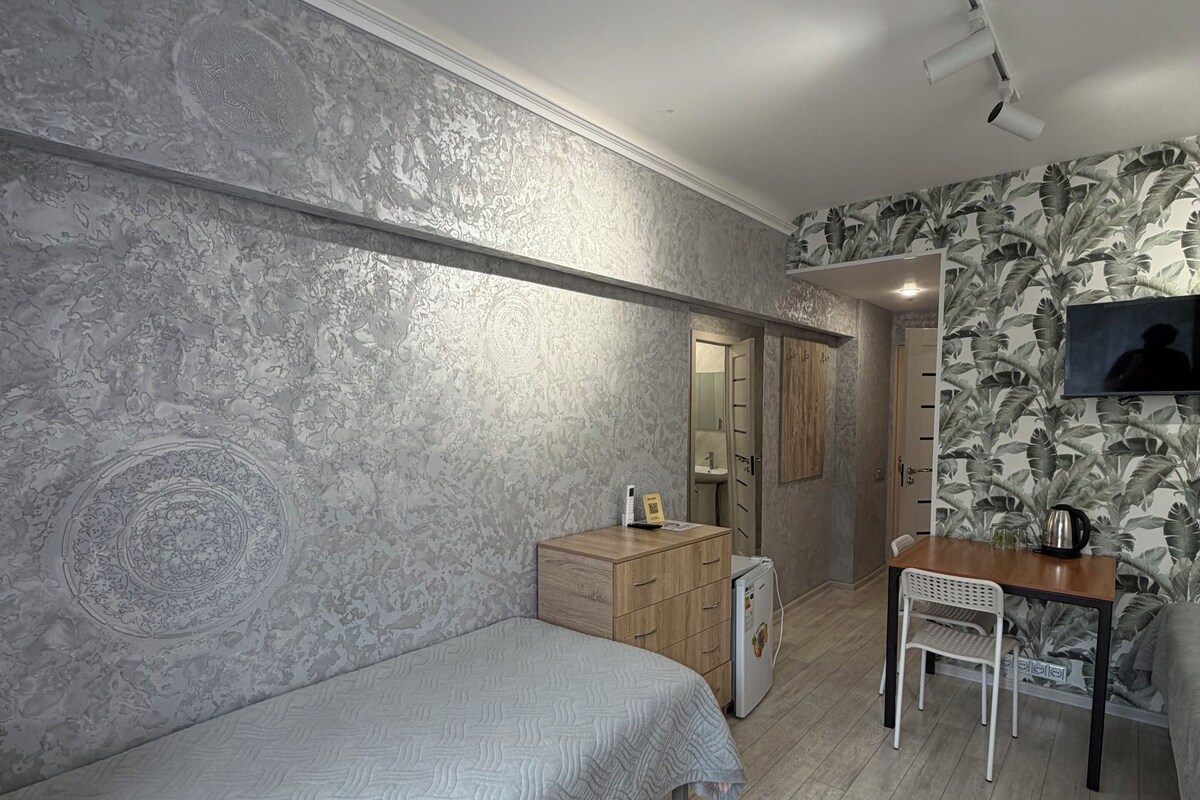 A bedroom with a bed, a desk, a chair, a wardrobe, and a television.