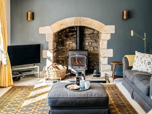 Ein gemütliches Wohnzimmer mit Kamin aus Stein, einer Couch, einem Fernseher und einem Couchtisch.