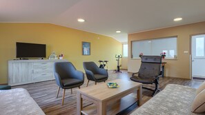 A living room with a sofa, two armchairs, a coffee table, a TV, a cabinet, and exercise equipment. - Casa Aneri by Villas Guide (Pavicini)
