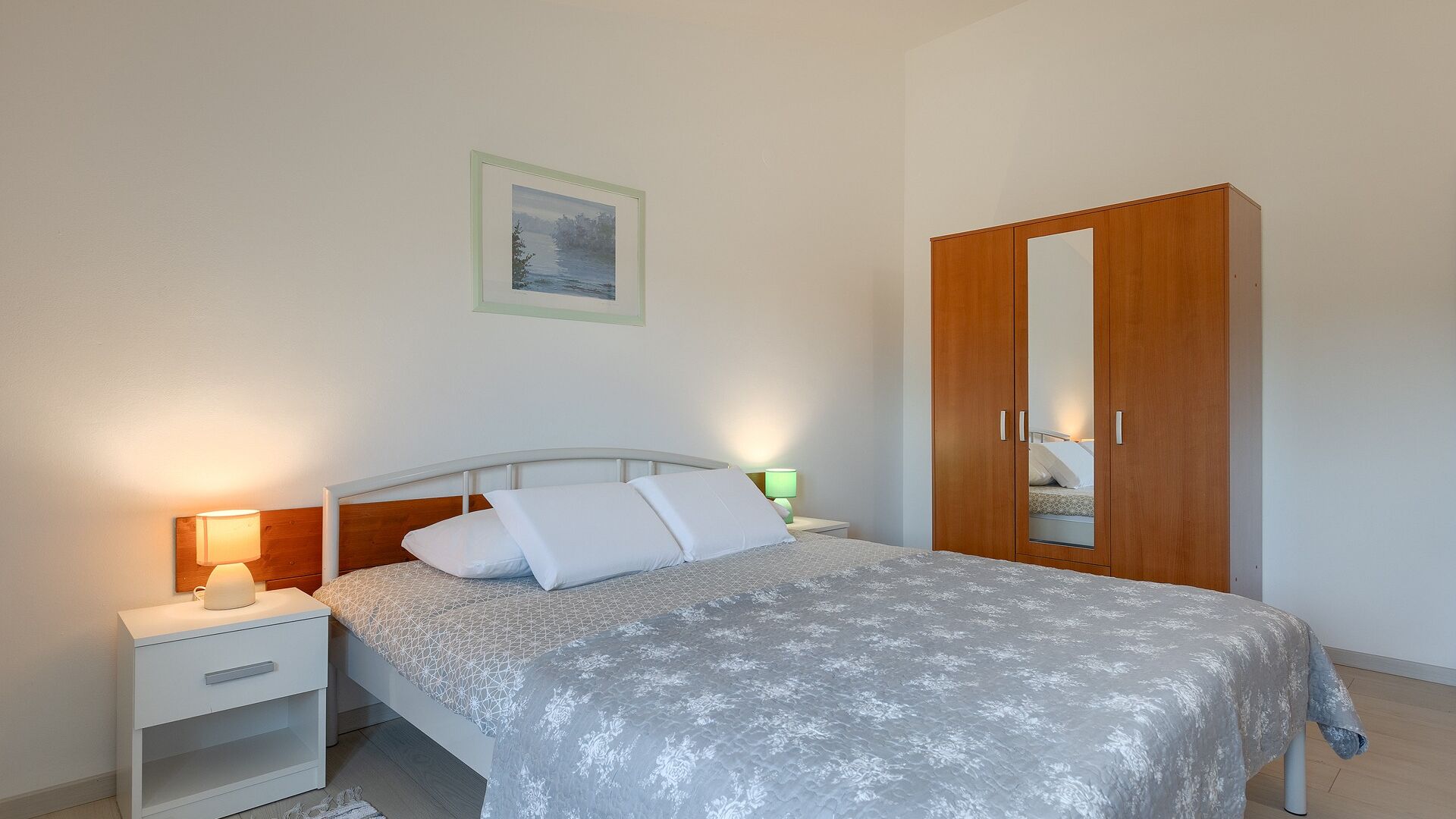 Une chambre à coucher avec un lit, des tables de chevet, une armoire et un tableau encadré au mur.