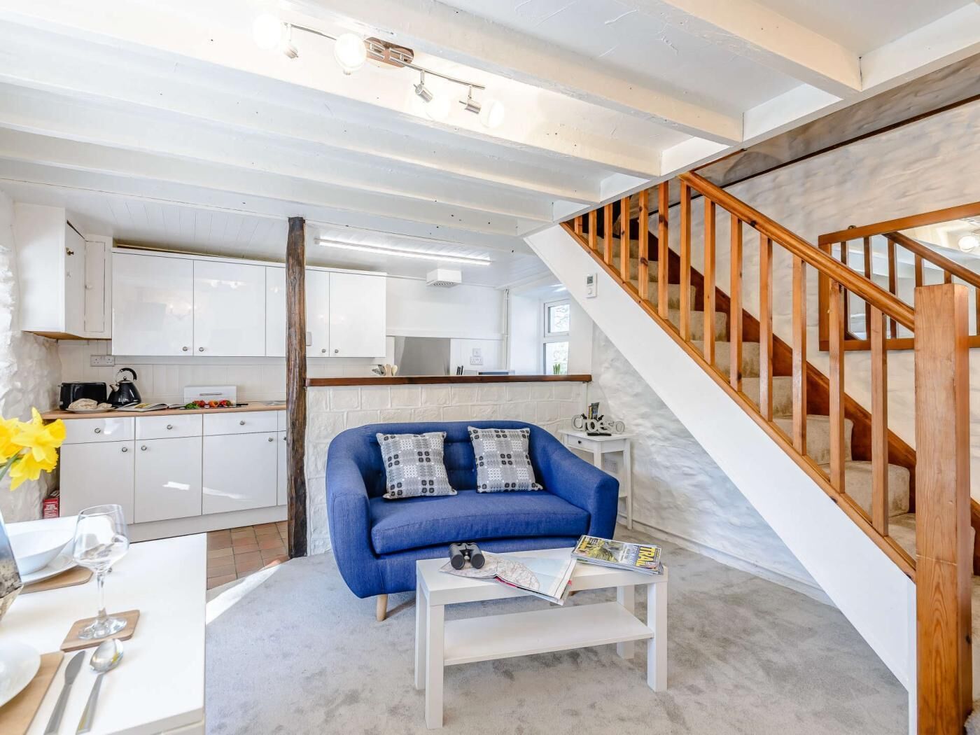Ein modernes Interieur mit einem blauen Sofa, einem weißen Couchtisch und einer Holztreppe.