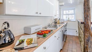 Une cuisine moderne avec des meubles blancs, une bouilloire, un four à micro-ondes et un évier.