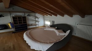 Et soveværelse med en seng, trægulv, et vindue og en radiator.
