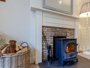 A room with a fireplace, a basket of firewood, and a lamp.