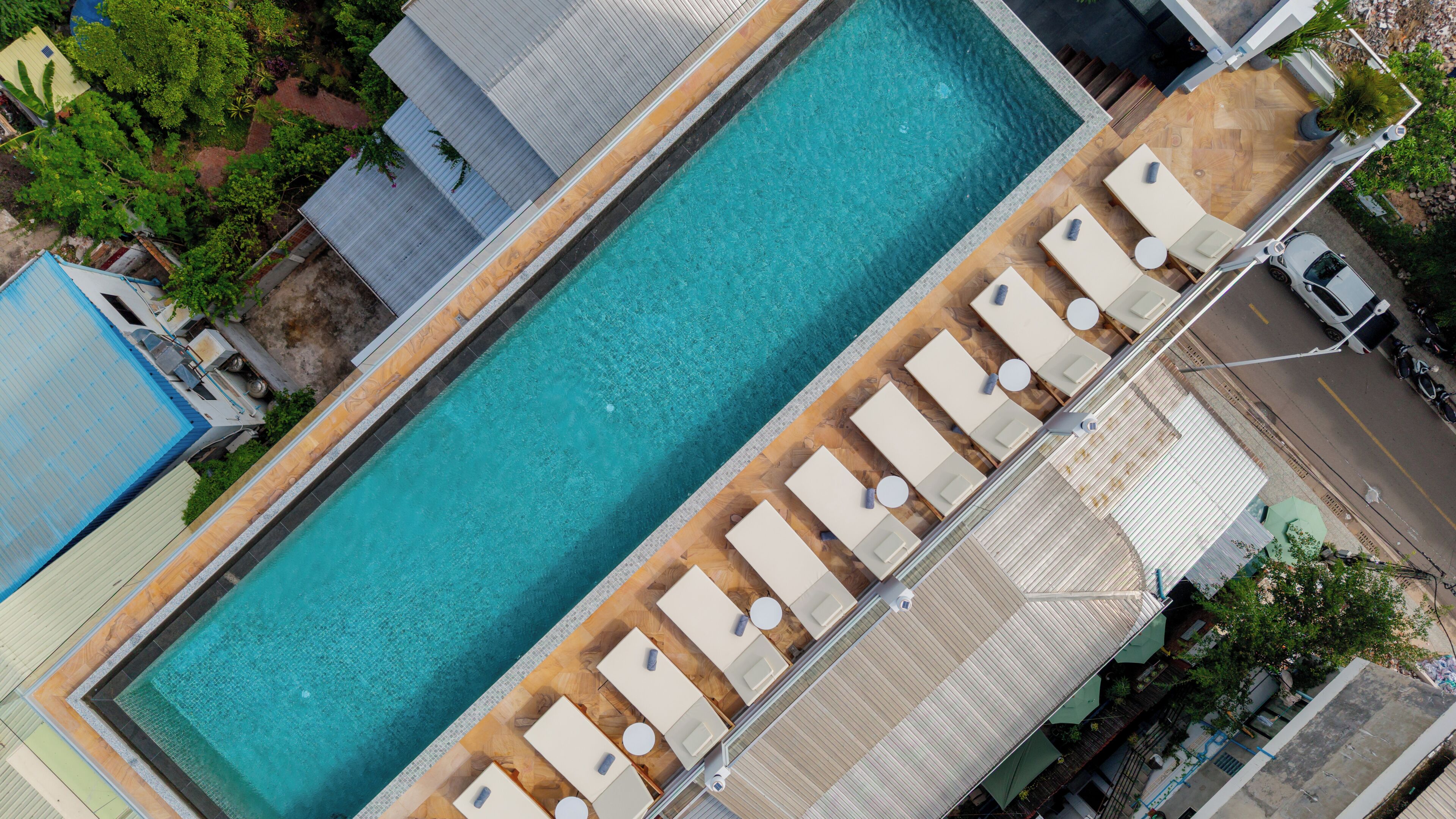 Ein rechteckiger Pool mit Holzterrasse und Liegestühlen am Rand.