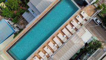 Ein rechteckiger Pool mit Holzterrasse und Liegestühlen am Rand.