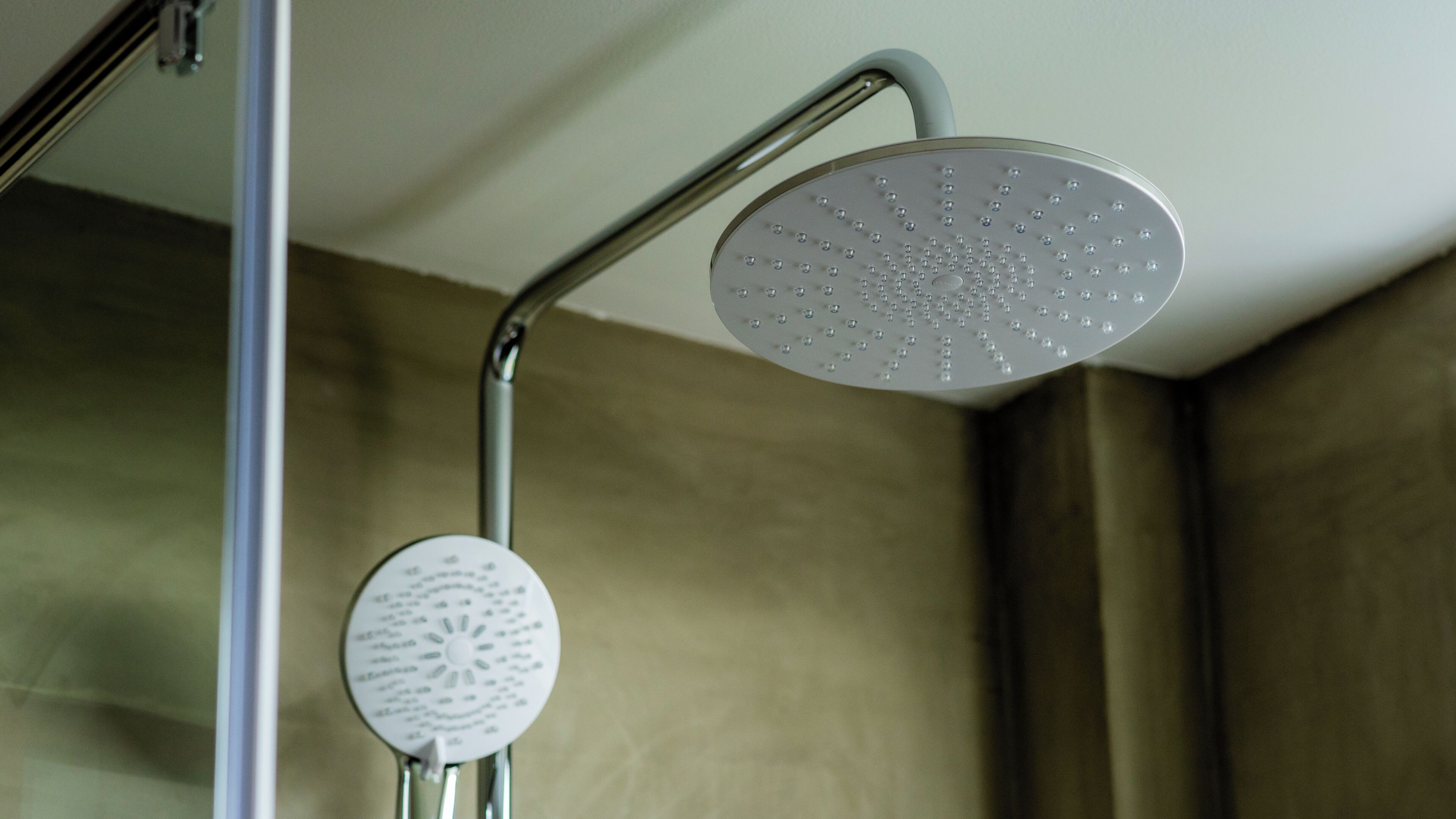 A shower with a rain showerhead and a handheld showerhead.