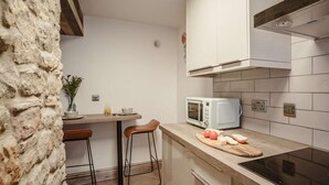 A compact kitchen with a microwave, a cutting board with tomatoes, and a stove. - 2 Bed in Morpeth (oc-82238) (Rothbury)