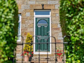 A stone building with a green door, potted plants, and a small window. - 4 Bed in Whitby (oc-82262) (Danby)