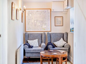 Een knusse woonkamer met twee grijze fauteuils, een klein houten tafeltje en een grote inlijstte kaart aan de muur.