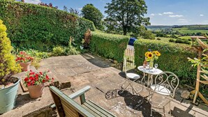 A patio with a table and chairs, a bench, and potted plants.