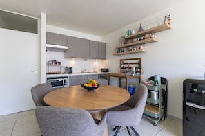 A modern kitchen with grey cabinets, a wooden dining table with four chairs, and a fruit bowl. - 1 bedroom accommodation in Oostduinkerke (Oostduinkerke)