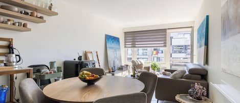 Eine moderne Küche mit Essbereich, einer Couch und Blick auf die Stadt.