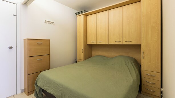 A bedroom with a bed, a wooden wardrobe, and a small cabinet. - 1 bedroom accommodation in Oostduinkerke (Oostduinkerke)