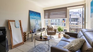 A living room with a sofa, armchair, coffee table, and artwork on the wall. - 1 bedroom accommodation in Oostduinkerke (Oostduinkerke)