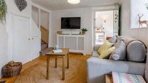 A living room with a sofa, a television, a patterned rug, and a staircase. - 1 Bed in Chulmleigh (oc-82389) (Chulmleigh)