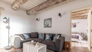 Un saló amb un sofà, una taula de centre i una làmpada. Hi ha un quadre a la paret i una porta que dona a una altra habitació.