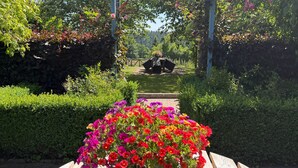Un jardí amb una taula de fusta, una testosa de flors i una paret de pedra.