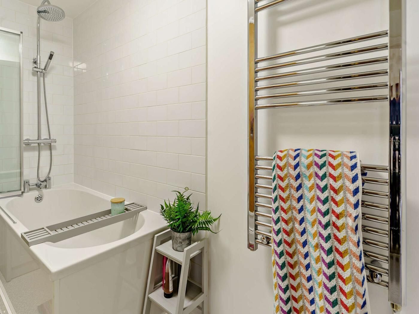 Uma casa de banho moderna com banheira, chuveiro e porta-toalhas.