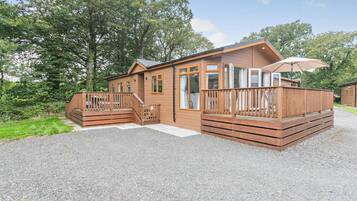Une cabane en bois dotée d’une terrasse, d’un patio couvert et d’une allée en gravier.