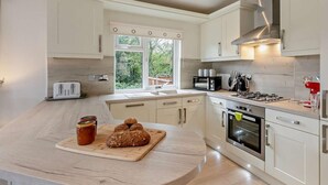 A modern kitchen with a central island, built-in appliances, and a view of greenery outside.