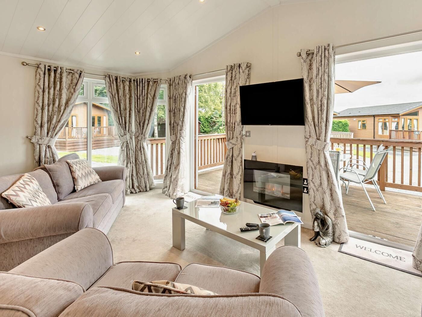 A spacious living room with a sofa, coffee table, and a flat-screen TV mounted above a fireplace.