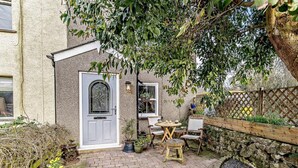 Eine Ziegelterrasse mit einer Tür, einem kleinen Tisch und Stühlen.