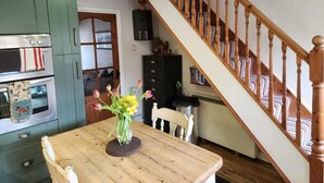 Eine Küche mit einem Holztisch, einem Blumenstrauß und einer Treppe.