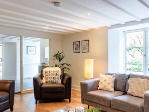 Un salon moderne avec un fauteuil en cuir, un canapé gris et une grande fenêtre laissant entrer la lumière naturelle.