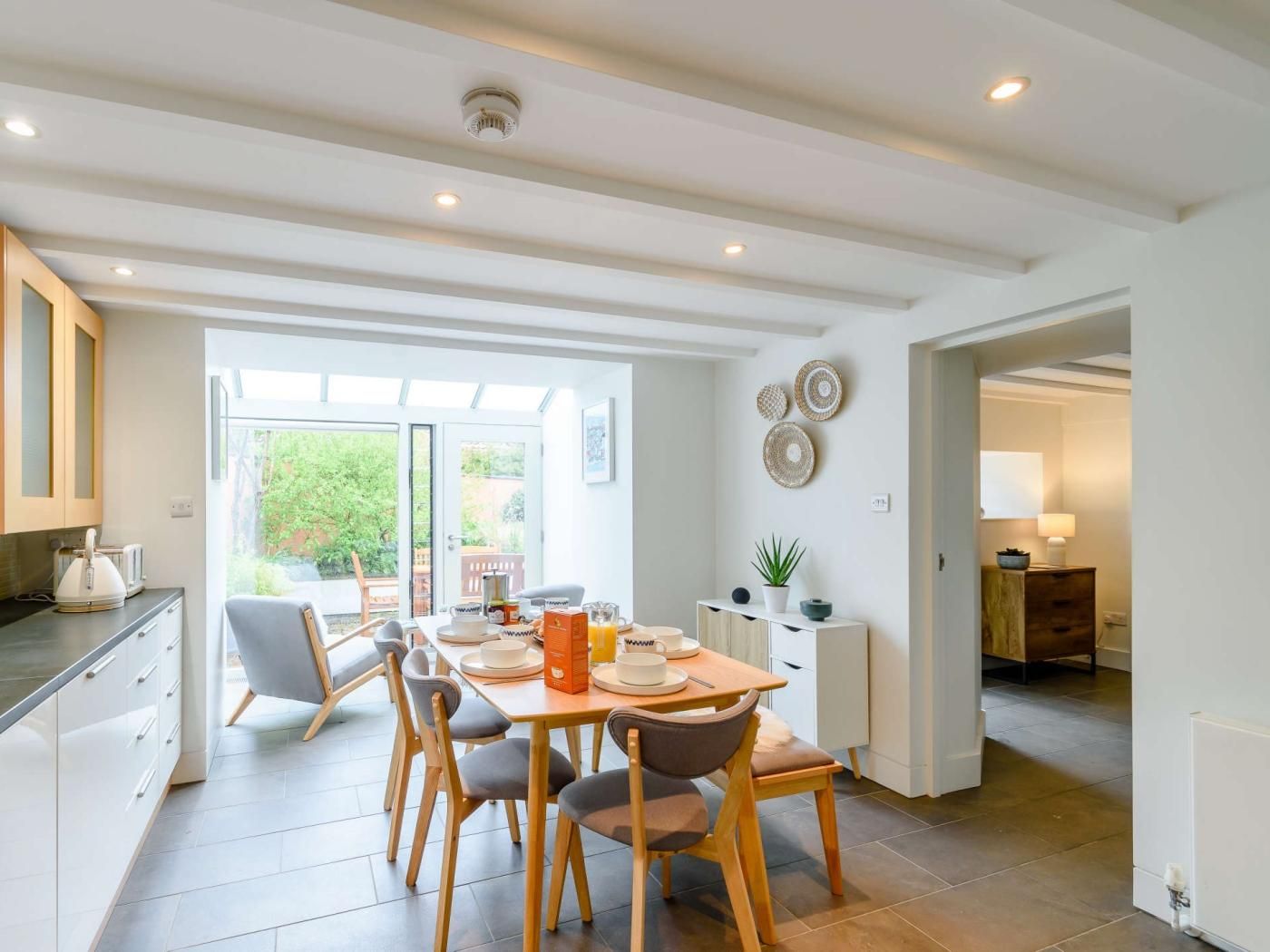 A modern kitchen with a dining area, featuring a large window, a built-in oven, and a countertop with a kettle.