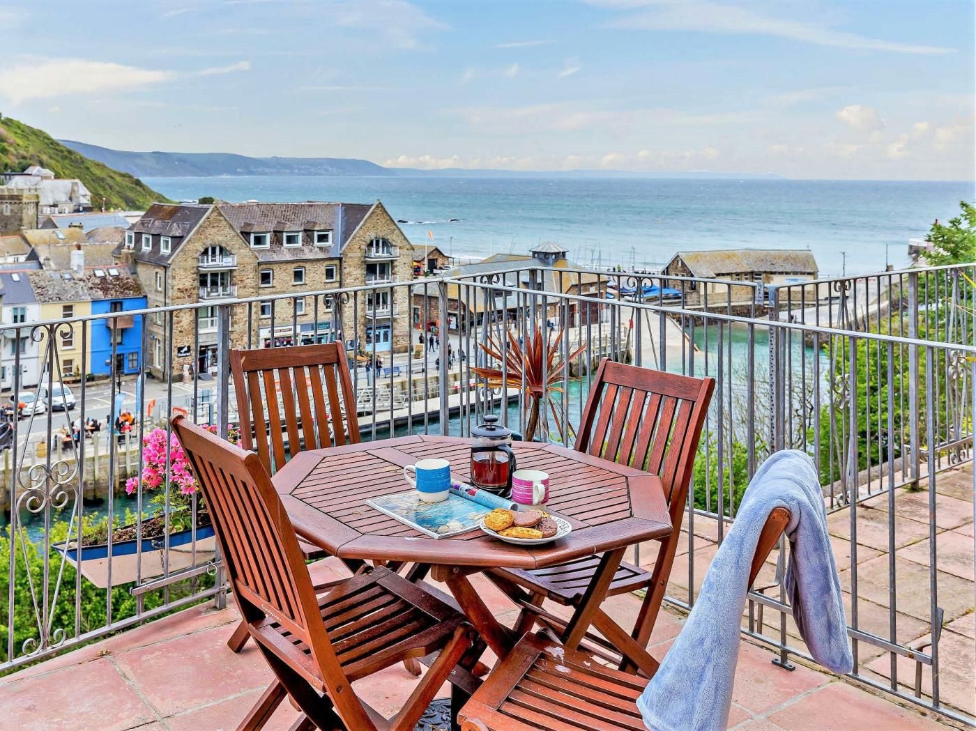 Ein Balkon mit Tisch, Stühlen und Blick auf das Meer und die Gebäude.