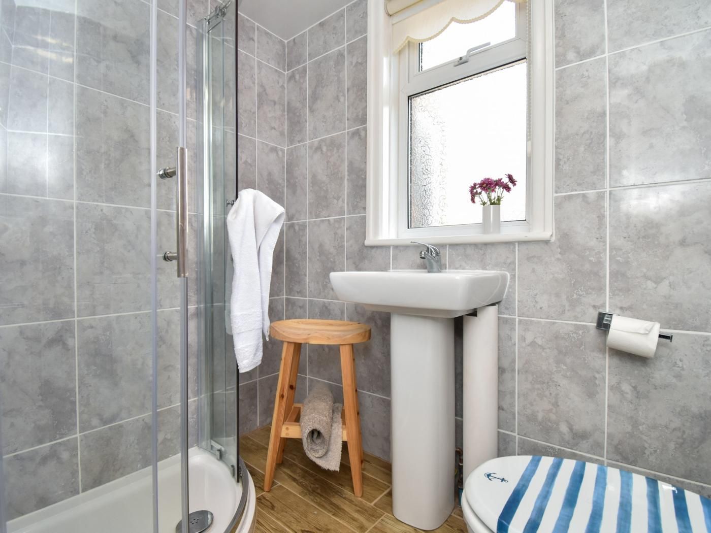 A bathroom with a shower, a sink, a toilet, and a window with a view.