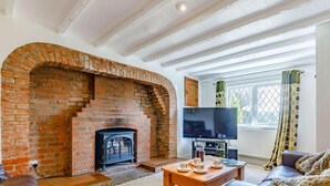 A living room with a brick fireplace, a television, a sofa, and a table with cups and saucers. - 2 Bed in Ashbourne (oc-82579) (Longford)