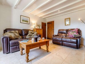 Ein Wohnzimmer mit zwei Ledersofas, einem Holztisch und einem gerahmten Bild an der Wand.
