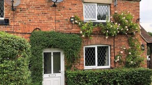 A brick house with a white door, a window with a diamond pattern, and a satellite dish. - 2 Bed in Ashbourne (oc-82579) (Longford)