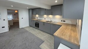 A modern kitchen with grey cabinets, a wooden countertop, and a built-in oven. - Modern Edinburgh City Escape | Sleeps 2 (Edinburgh)