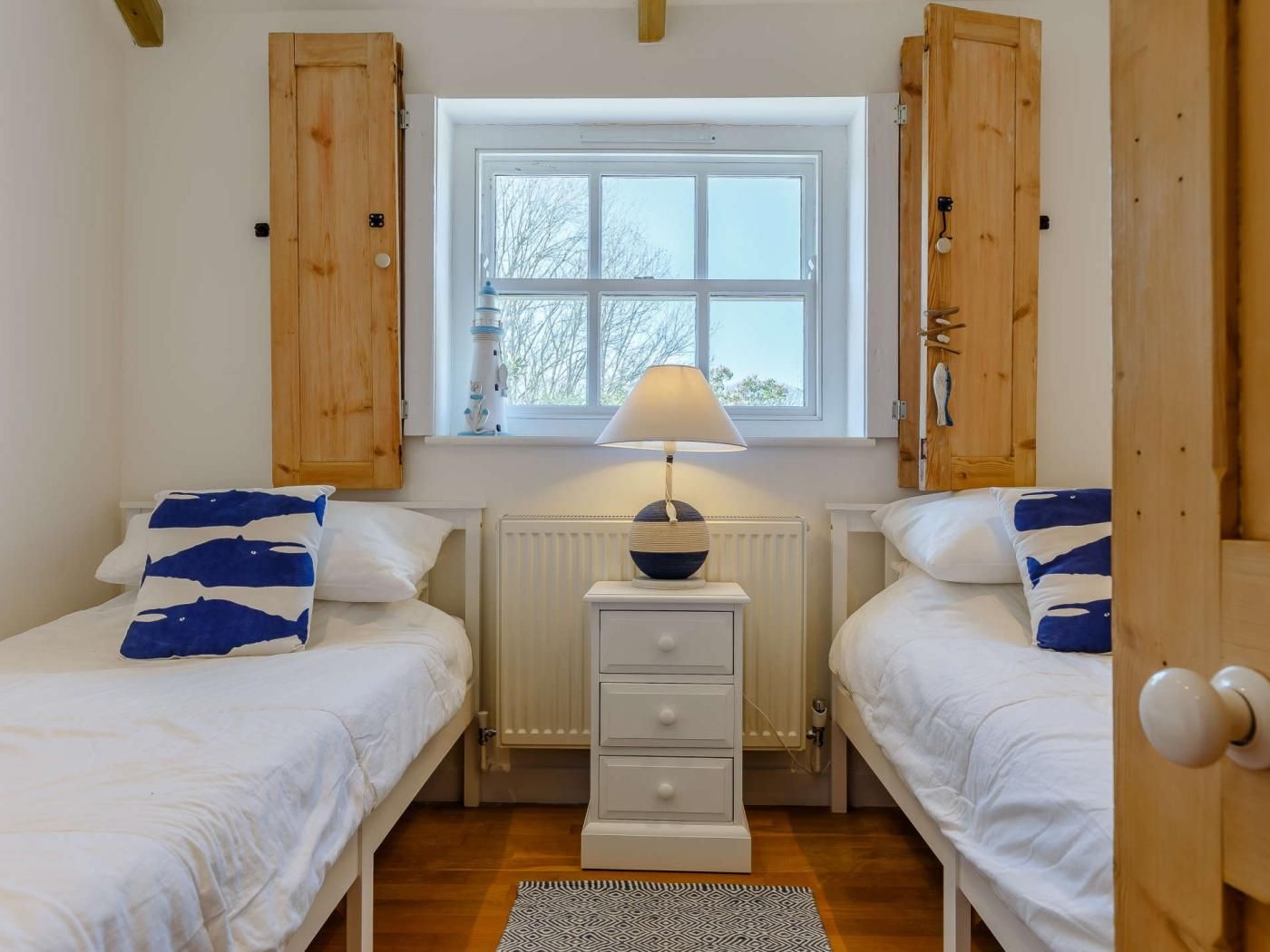 Un dormitorio con dos camas, una ventana, una lámpara y armarios de madera.