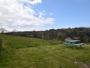 A picnic table in a grassy field with a hill and trees in the background. - 2 Bed in Wadebridge (oc-82681) (Little Petherick)